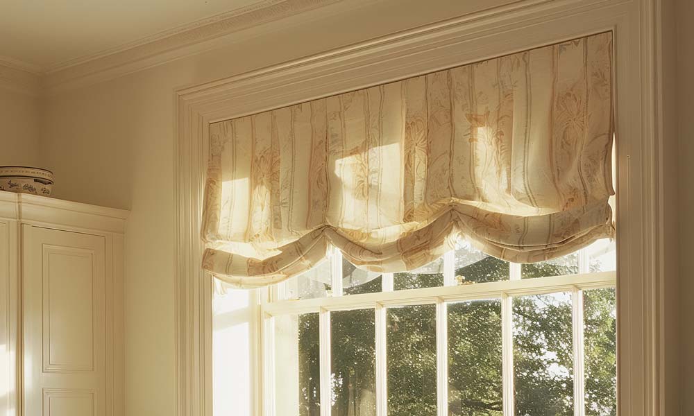 Elegant fabric valance over sunlit window in classic kitchen