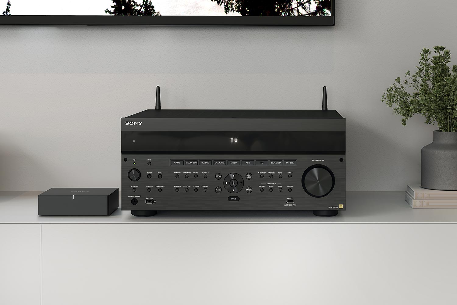 A Sony AV receiver with detailed controls, placed on a white cabinet next to a media device and greenery.