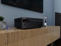 A Sony AV receiver placed on a wooden console table, paired with a sleek remote control and decorative items.